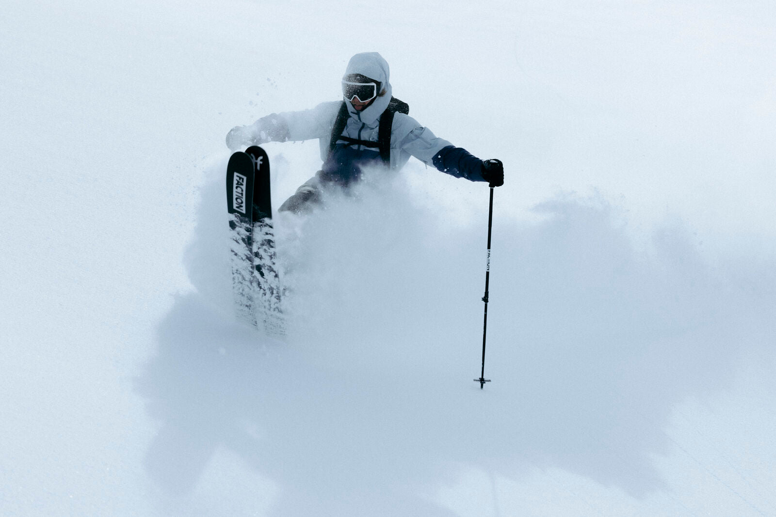 Someone skiing powder with faction skis doing a manual