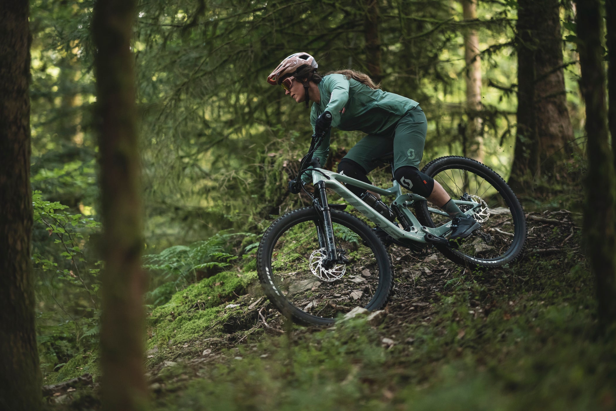 riding a scott contessa mountain bike through a mossy green forest
