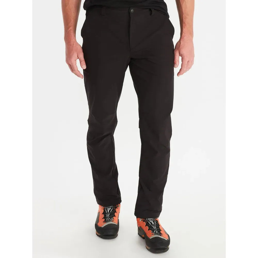 A pair of Marmot men's scree softshell pants in black color, featuring a slim fit and displayed on a male model with boots.