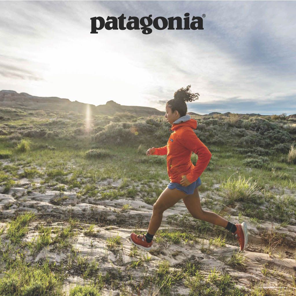 a women running in neat lighting with the patagonia logo in a torentshell rain jacket