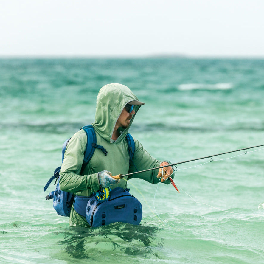 someone flyfishing in a patagonia sunshirt in the tropics with a patagonia logo in the corner